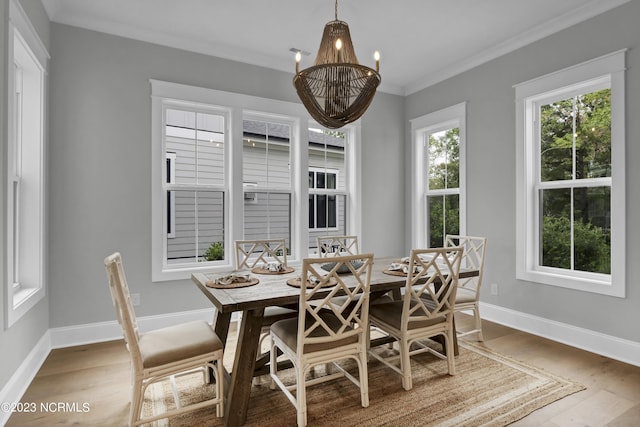 dining space with wood-type flooring, an inviting chandelier, and ornamental molding