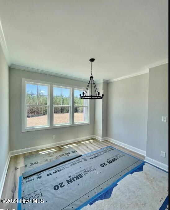 interior space featuring an inviting chandelier, ornamental molding, and wood-type flooring