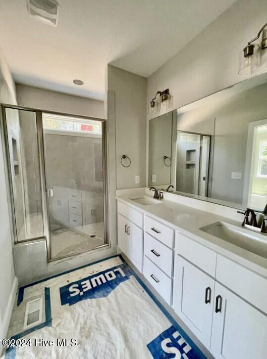 bathroom featuring a shower with door and vanity