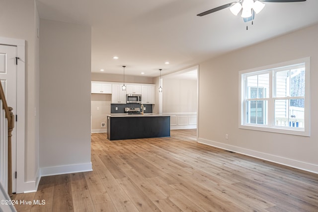 1725 Longleaf Dr E, Pinehurst, NC 28374 - kitchen featuring ceiling fan, backsplash, appliances with stainless steel finishes, white cabinets, and light wood-style floors