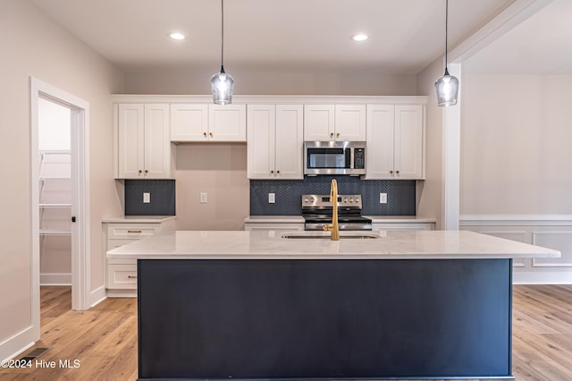 kitchen with a sink, white cabinets, light wood finished floors, and stainless steel appliances