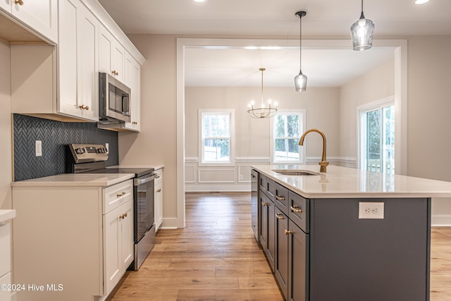 kitchen featuring a sink, light countertops, light wood-style floors, appliances with stainless steel finishes, and white cabinetry