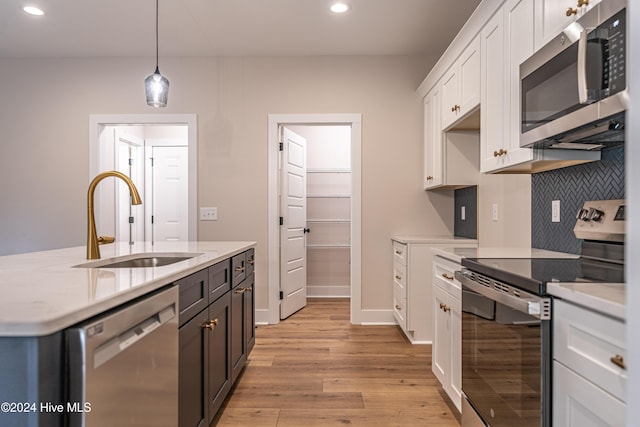 1725 Longleaf Dr E, Pinehurst, NC 28374 - kitchen featuring appliances with stainless steel finishes, a sink, light wood-style floors, recessed lighting, and white cabinetry