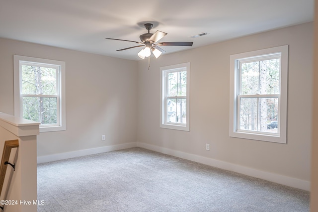 carpeted spare room with a wealth of natural light, visible vents, and baseboards