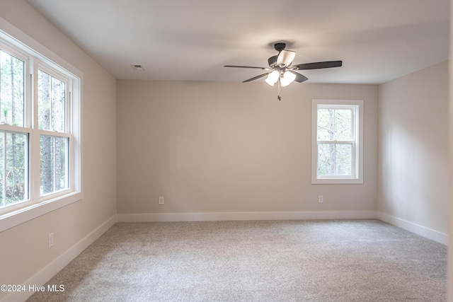 carpeted empty room with baseboards, visible vents, and ceiling fan