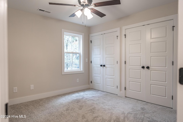 unfurnished bedroom with visible vents, two closets, a ceiling fan, carpet flooring, and baseboards