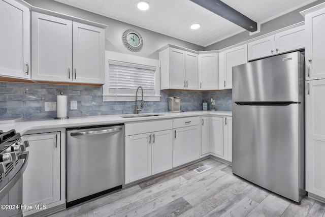 kitchen with light hardwood / wood-style floors, beam ceiling, sink, stainless steel appliances, and white cabinets