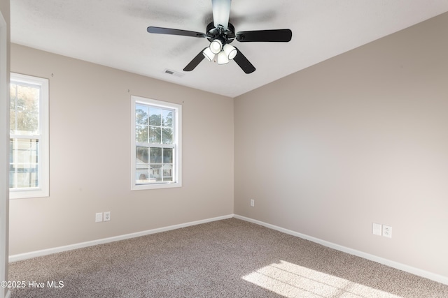 carpeted spare room featuring a wealth of natural light and ceiling fan