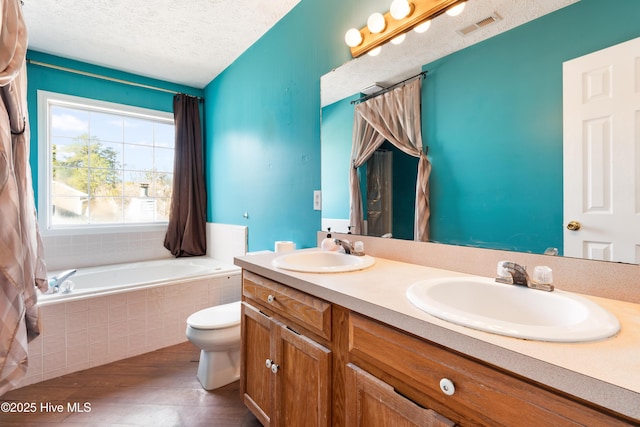 bathroom featuring toilet, a textured ceiling, vanity, tiled tub, and hardwood / wood-style floors