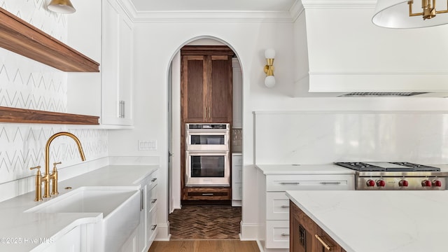 kitchen with light stone counters, stainless steel appliances, white cabinets, and sink