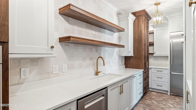 kitchen with hanging light fixtures, stainless steel appliances, tasteful backsplash, white cabinets, and sink