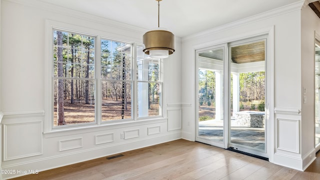 unfurnished dining area featuring light wood-type flooring and crown molding