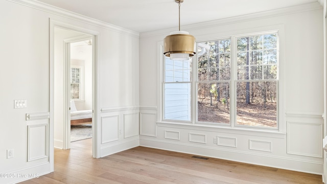 unfurnished dining area featuring ornamental molding and light wood-type flooring