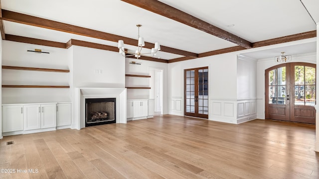 unfurnished living room with french doors, a chandelier, and light wood-type flooring