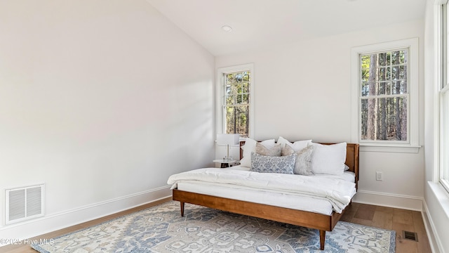 bedroom with lofted ceiling, hardwood / wood-style flooring, and multiple windows