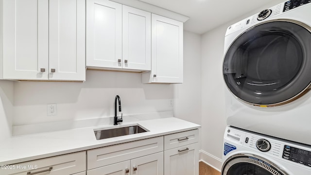 laundry area with stacked washer and clothes dryer, cabinets, and sink