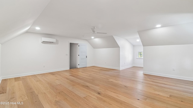 additional living space with ceiling fan, vaulted ceiling, light hardwood / wood-style flooring, and a wall mounted AC