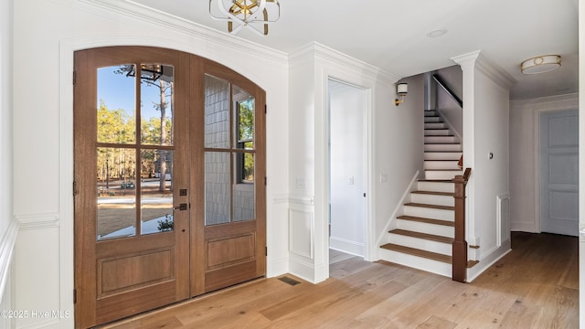 entrance foyer featuring ornamental molding, light wood-type flooring, french doors, and a chandelier