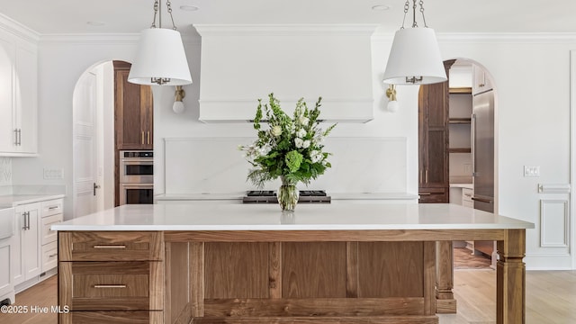 kitchen featuring double oven, white cabinets, a center island, and hanging light fixtures