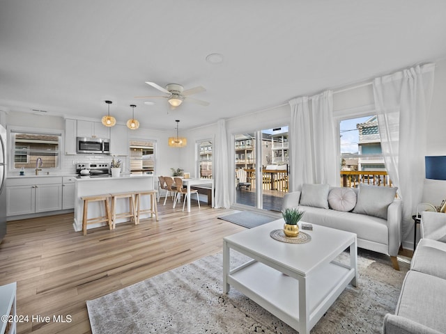 living room with ceiling fan, light hardwood / wood-style floors, and sink