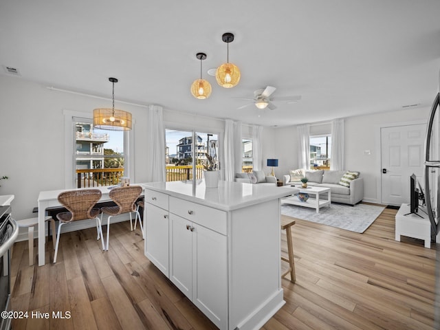 kitchen featuring hanging light fixtures, plenty of natural light, white cabinets, and light hardwood / wood-style floors