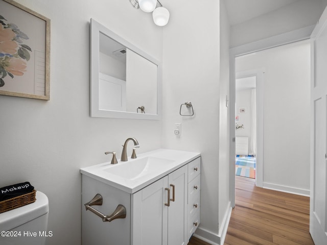 bathroom with wood-type flooring, vanity, and toilet