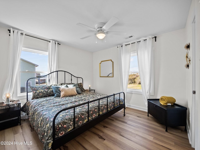 bedroom with multiple windows, ceiling fan, and light wood-type flooring