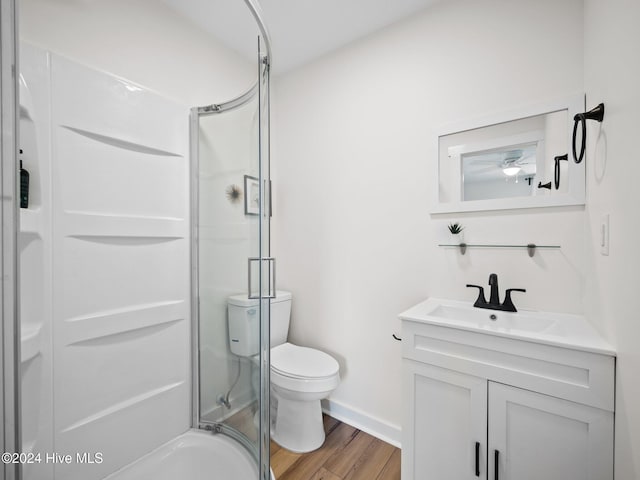 bathroom featuring wood-type flooring, vanity, toilet, and a shower with door