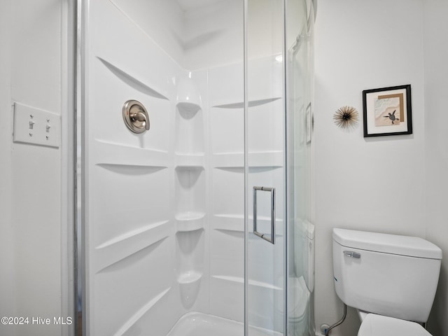 bathroom with a shower with shower door and toilet