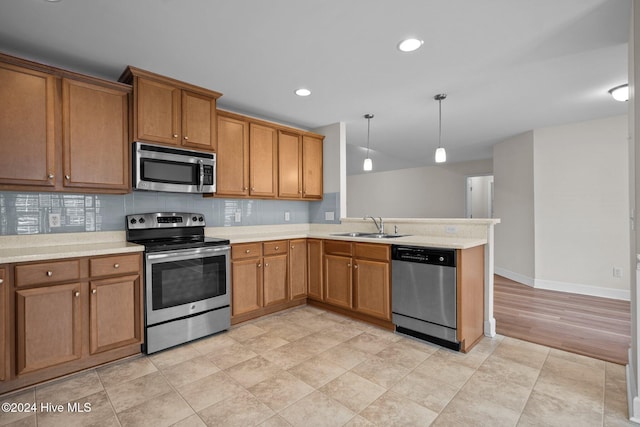 kitchen with sink, decorative backsplash, decorative light fixtures, kitchen peninsula, and stainless steel appliances