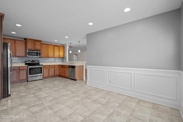 kitchen featuring sink, hanging light fixtures, backsplash, kitchen peninsula, and appliances with stainless steel finishes