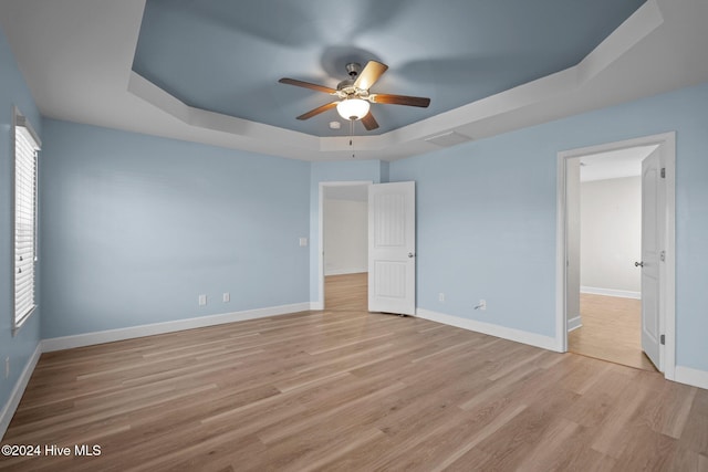 unfurnished bedroom featuring ceiling fan, light hardwood / wood-style floors, and a raised ceiling