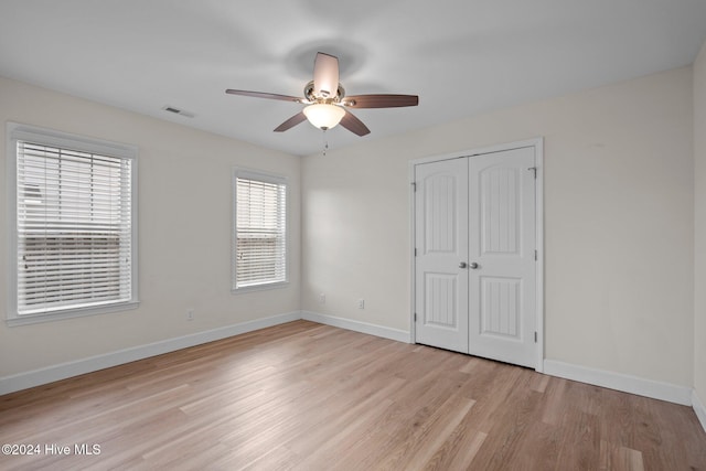 unfurnished bedroom with ceiling fan, light wood-type flooring, and a closet