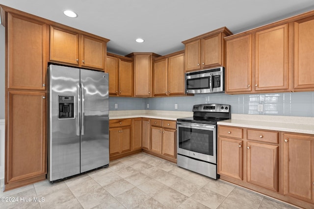 kitchen with backsplash, light tile patterned flooring, and appliances with stainless steel finishes