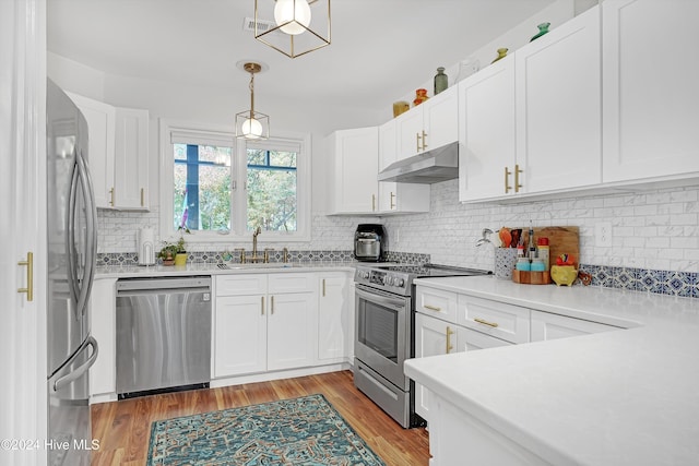 kitchen featuring white cabinets, appliances with stainless steel finishes, light wood-type flooring, and pendant lighting