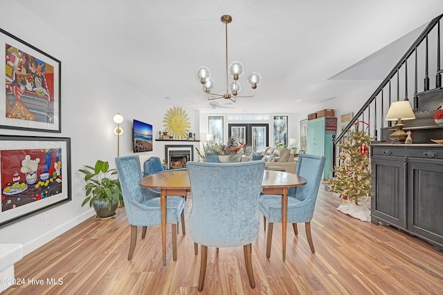 dining room featuring ceiling fan with notable chandelier and light hardwood / wood-style floors