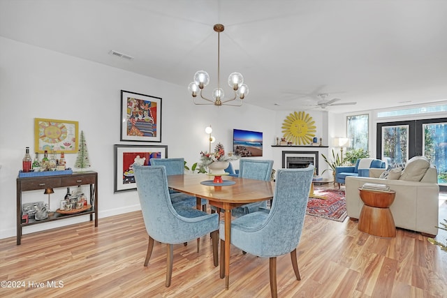 dining room with ceiling fan with notable chandelier and light wood-type flooring