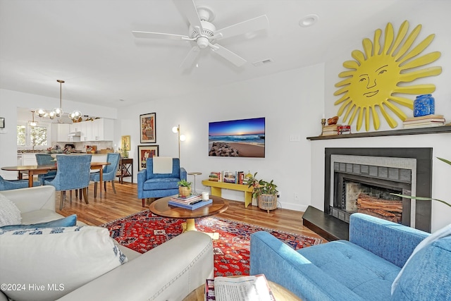 living room featuring ceiling fan with notable chandelier and hardwood / wood-style flooring