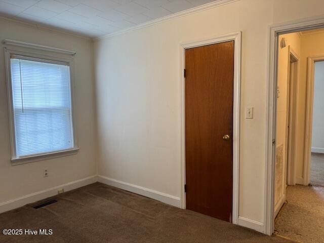 unfurnished room with baseboards, visible vents, carpet floors, and ornamental molding
