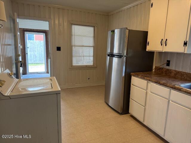 kitchen with white cabinetry, wood walls, dark countertops, freestanding refrigerator, and light floors