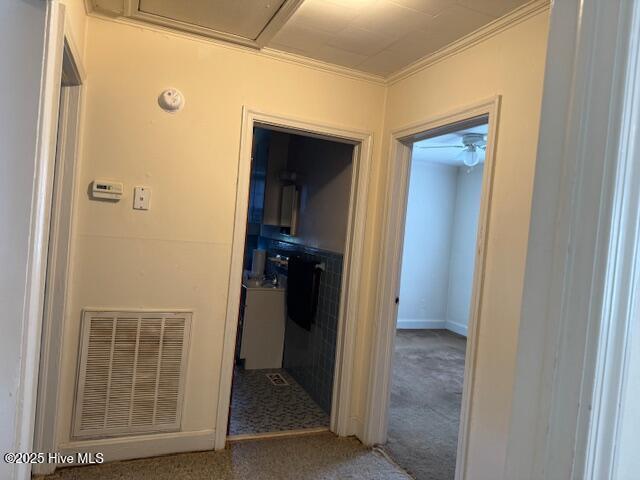 hallway with visible vents, crown molding, and carpet