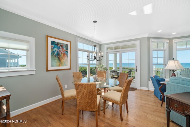 dining room featuring crown molding, a water view, light hardwood / wood-style floors, and a notable chandelier