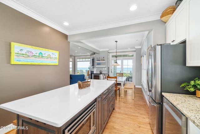 kitchen with a healthy amount of sunlight, appliances with stainless steel finishes, hanging light fixtures, and white cabinets