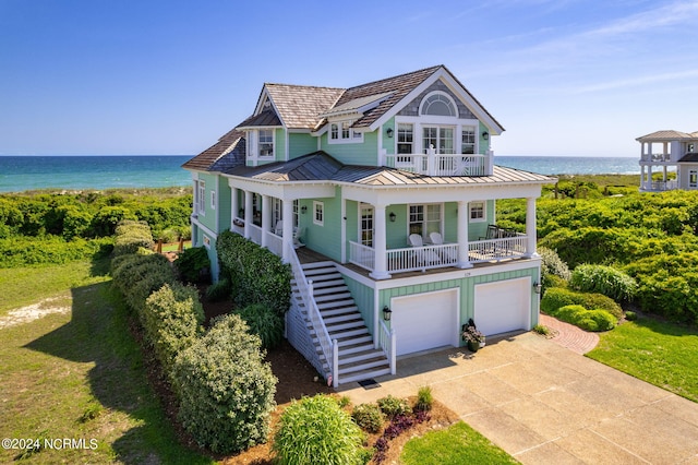 view of front of house featuring a water view, a garage, covered porch, and a front lawn