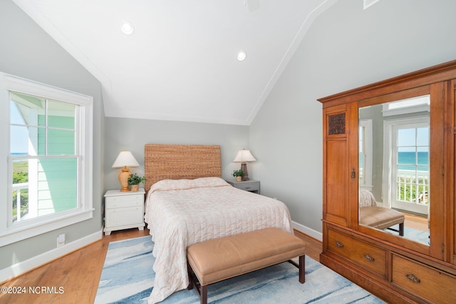 bedroom with light hardwood / wood-style flooring, crown molding, vaulted ceiling, and a water view