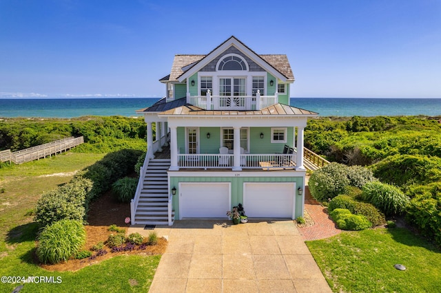 view of front of home featuring a water view, a balcony, a garage, and a front yard