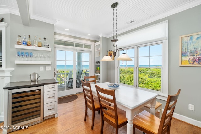 dining space with plenty of natural light, a water view, wine cooler, ornamental molding, and bar area