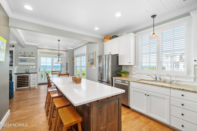 kitchen with decorative light fixtures, stainless steel appliances, beverage cooler, and a kitchen island