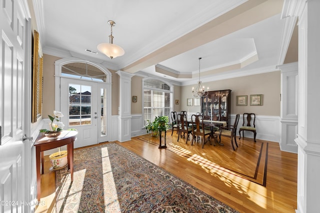 entryway with light wood-type flooring, crown molding, and decorative columns