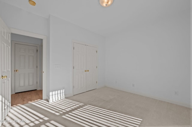 unfurnished bedroom with a closet and light colored carpet